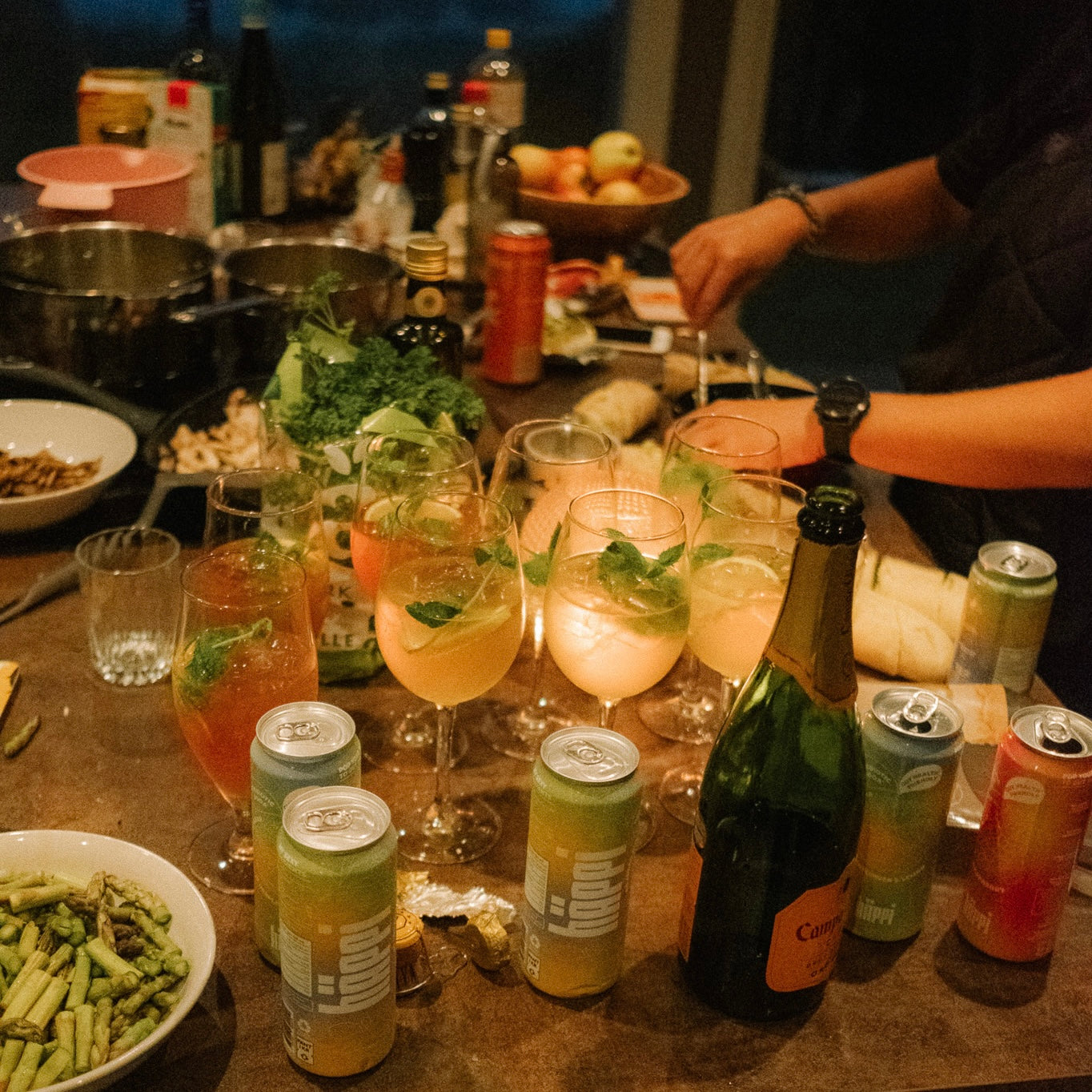 A cozy gathering with a table full of vibrant hÄppi prebiotic sodas, fresh ingredients, and cocktails garnished with mint, showcasing a lively and healthy social setting perfect for shared moments.
