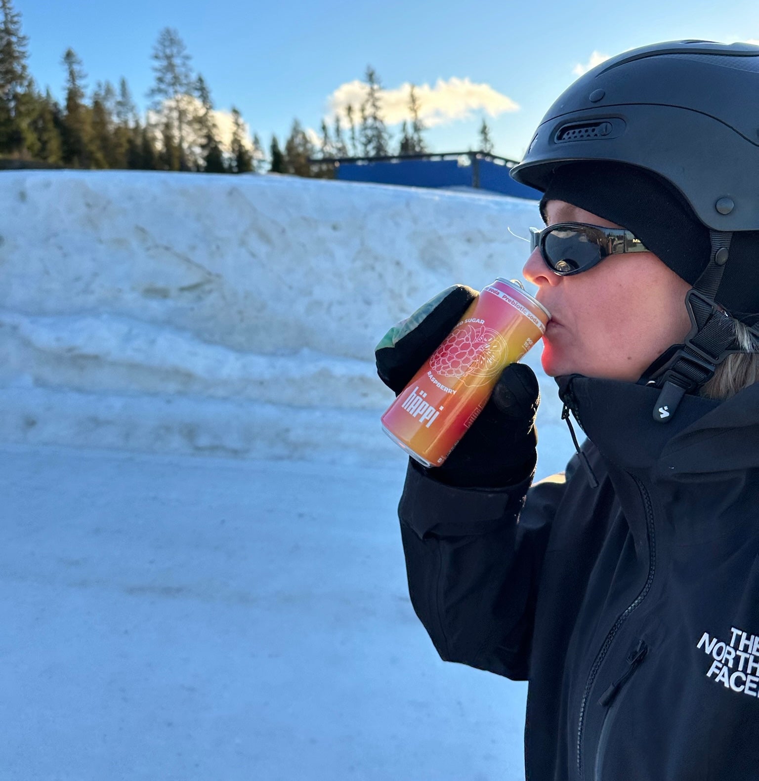 A person in winter gear enjoys a refreshing hÄppi prebiotic soda in a snowy outdoor setting, highlighting the perfect healthy drink for active, cold-weather adventures.