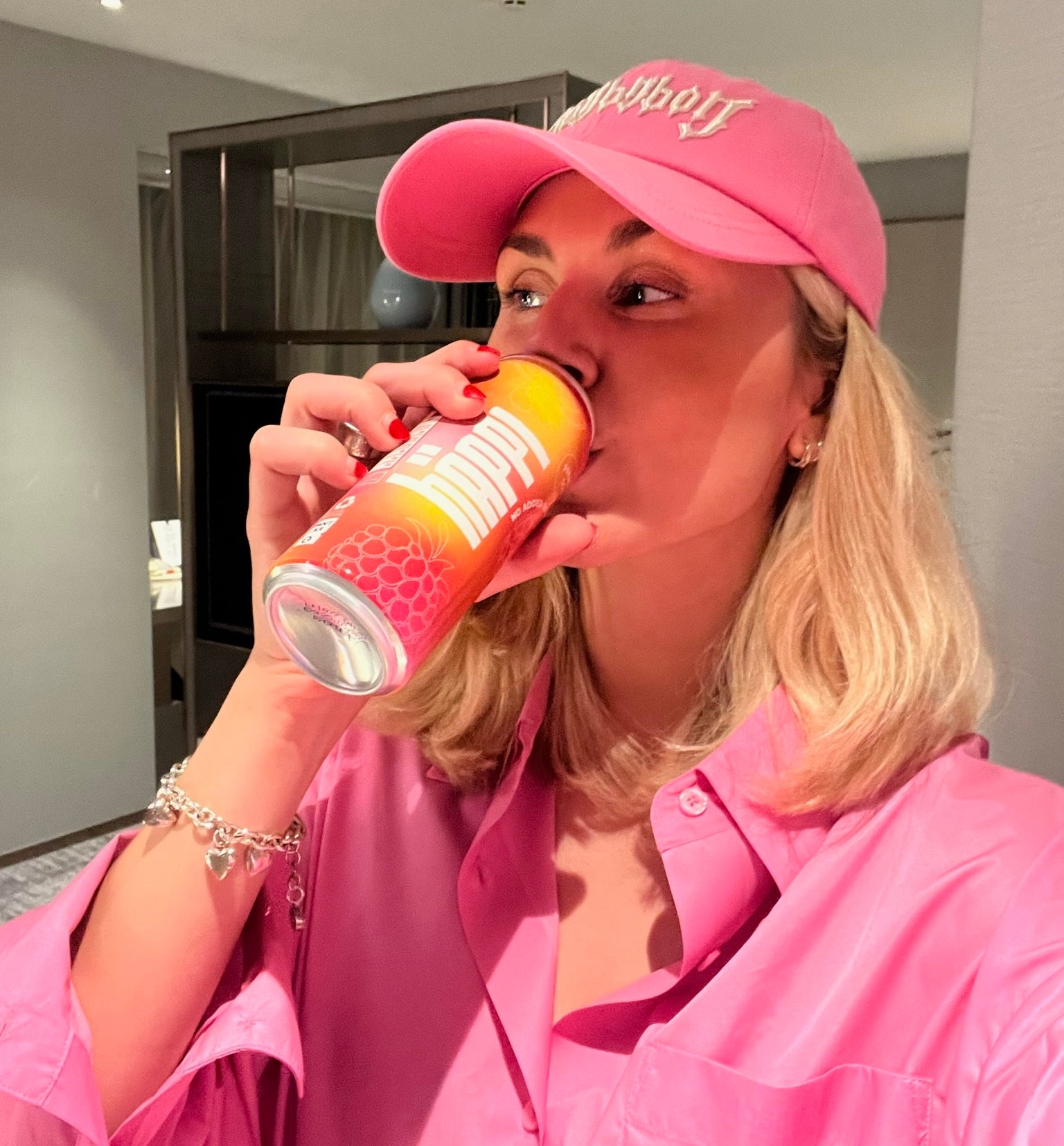Woman in pink drinks häppi prebiotic soda, boosting gut health with a refreshing, immune-boosting beverage.
